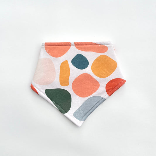Bandana bib in warm toned abstract print on white background